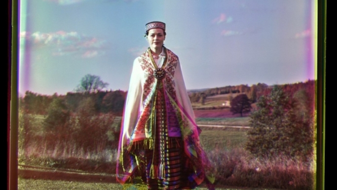 Sieviete tautastērpā iet pa zāli