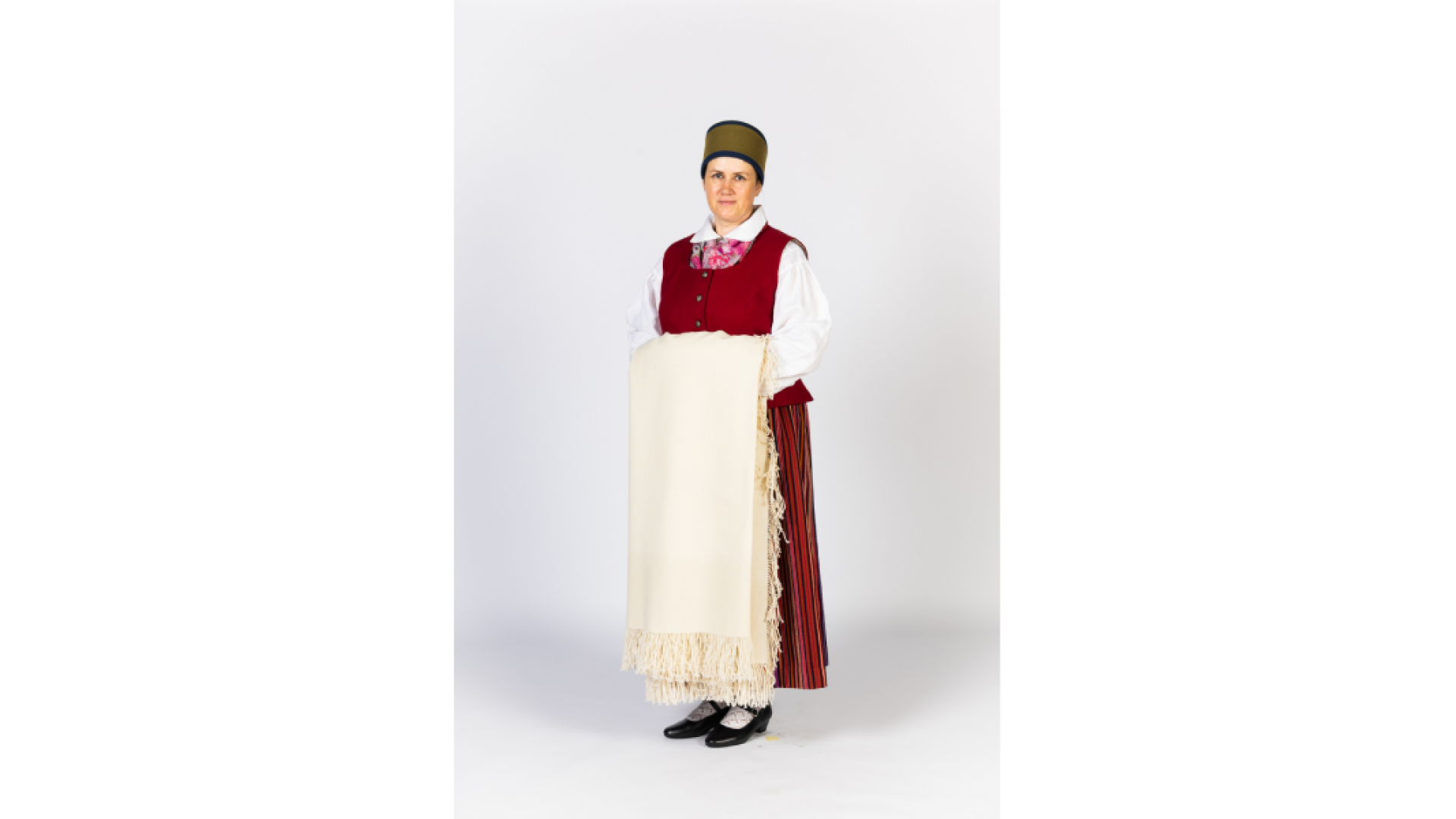 Piebalgas sievas tērps. Svītraini brunči, keklas, ņieburs, zeķes apavi, galvā ts "zaļmalīte" sievas cepure no melna un zaļa vilnas auduma, rokās austs, balts lakats ar bārkstīm.
