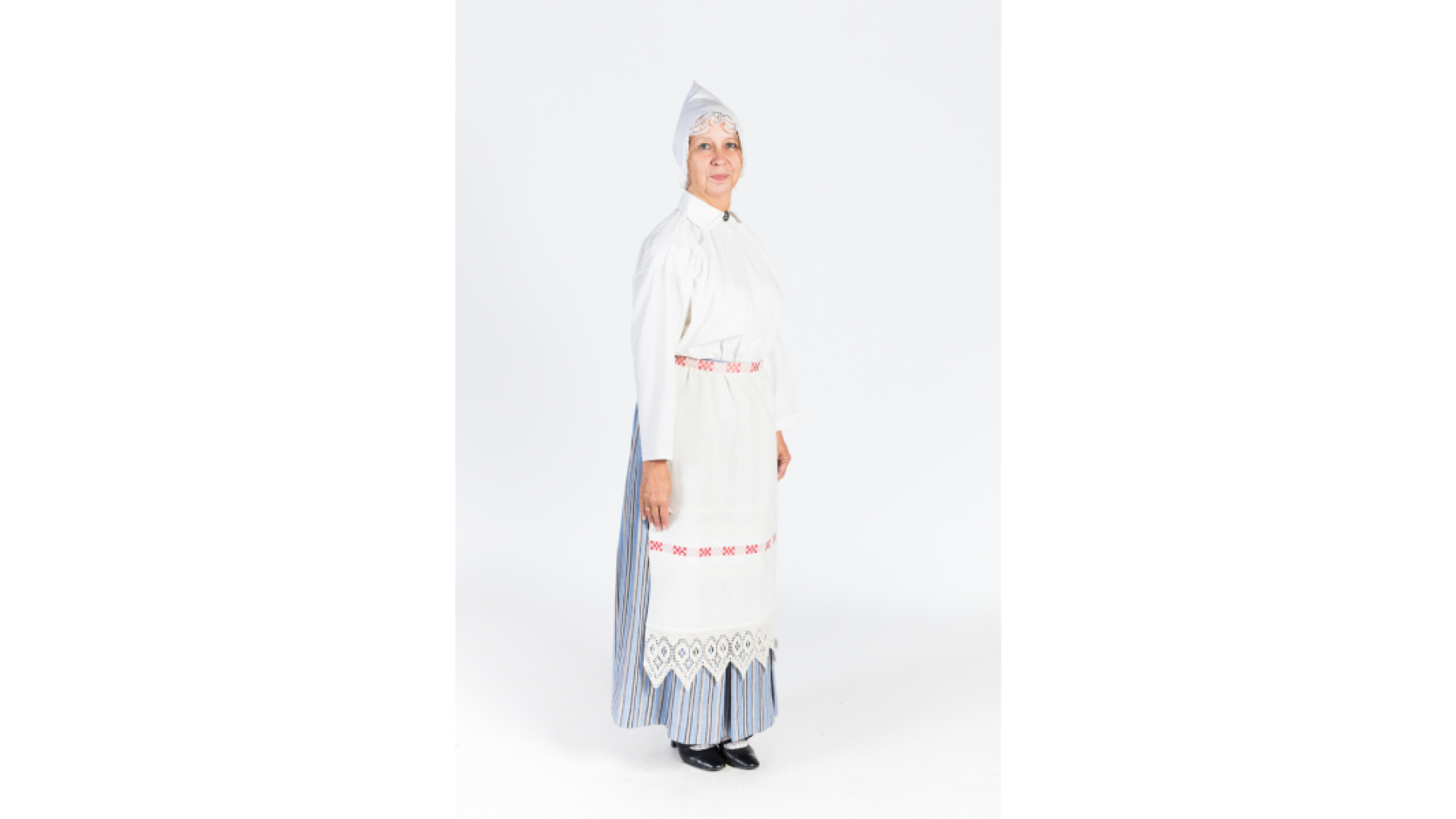 Sieva Vidzemes vasaras/darba tērpā. Vasaras tērps darināts no lina un kokvilnas auduma. Krekls, brunči, priekšauts ar rotājumu, galvā izšūta sievas cepure.