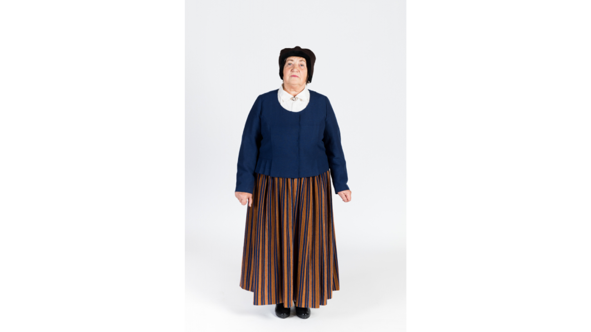 Sieva ziemas tērpā. Krekls, svītraini brunči, tumši zila auduma jaka, galvā siltā ziemas cepure.