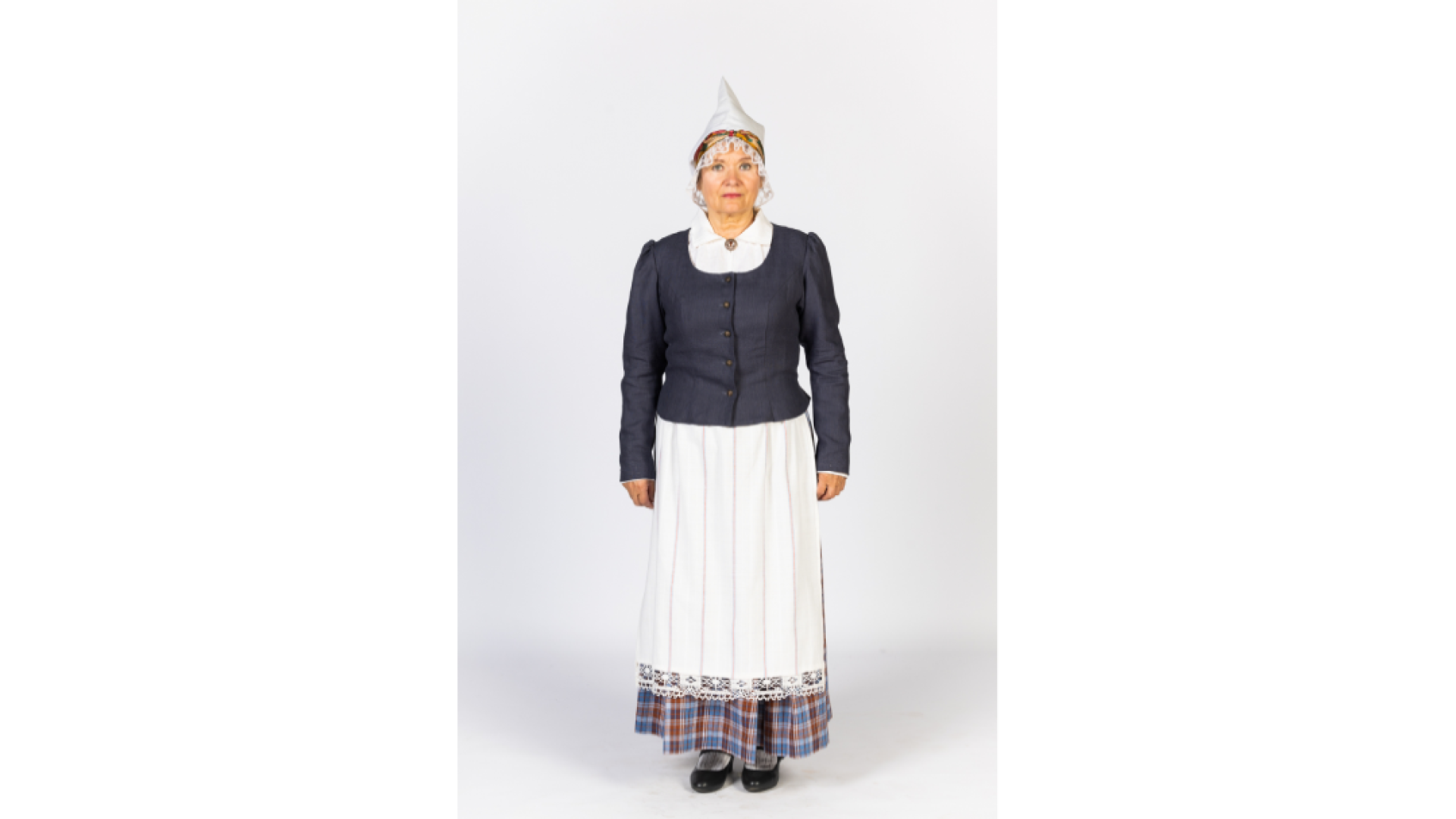 Vidzemes sievas tērps. Sievietei mugurā brunči, jaka, priekšā balts, rotāts priekšauts, galvā balta cepure.