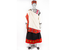 Sievietes manekens ar Bārtas sievas tērpu, kas sastāv no: ga;vā Bārtas sievas cepure - vainagcepure, mugurā krekls, ņieburs, brunči, villaine, kura sasprausta ar saktu uz labā pleca. Kājās baltas adītas zeķes un melnas kurpes.